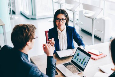 İki bayan meslektaşı, erkek finans müdürü ile önemli bir toplantı yapıyor. İçerideki ticaretin detaylarını tartışıyorlar. Bir grup ekonomist masaüstünde oturmuş istatistikler hakkında konuşuyorlar.