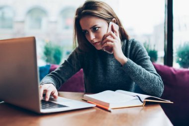 Uzaktan kumanda sırasında kafeteryada oturan profesyonel ciddi kadın metin yazarı iş arkadaşıyla konuşurken akıllı telefonda önemli bir konuşma için yeni bir uygulama kullanıyor.