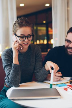 Gözlüklü çekici işkadını, rahat kafeteryadaki, teknoloji ve iletişim kavramının başarılı erkek arkadaşıyla gayri resmi görüşmeler sırasında cep telefonuyla sohbet ediyor.