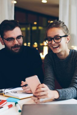 Genç hippiler sosyal ağlarda cep telefonuyla komik videolar izliyorlar üniversite kafeteryasında kablosuz bağlantıya bağlılar, akıllı telefondaki uyarıyı kontrol eden gülümseyen kız arkadaşlarıyla ders arası veriyor.