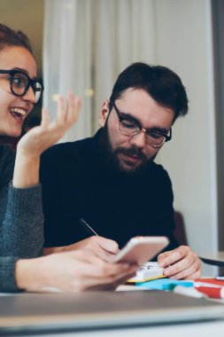 Bilgi aramak ve oteli internetten ayırtmak için not defteri ve cep telefonu kullanarak birlikte seyahat etmeyi planlayan iki pozitif öğrenci, neşeli hippi kız kafeteryada dinlenirken telefon bekliyor.