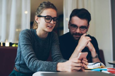 Genç bir erkek ve kadın üniversite kampüsünde çekici yeniyetme bir kızla iyi bağlantıları olan internet üzerinden oyun cep telefonu, cep telefonuyla internet sayfasına göz atan bir kadın.