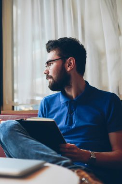 Genç düşünceli erkek gazeteci kafenin penceresine bakarken makale yazmayı düşünüyor. Üniversite kampüsünde arkadaşlarıyla birlikte ders çalışan düşünceli hippi çocuk.