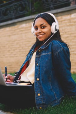 Açık havada istimal laptop için araştırma ödevi gülümseyen afro Amerikan öğrenci portresi. Hippi kız sınavları açık havada için hazırlanıyor Üniversitesi kampus içinde styling olumlu koyu derili