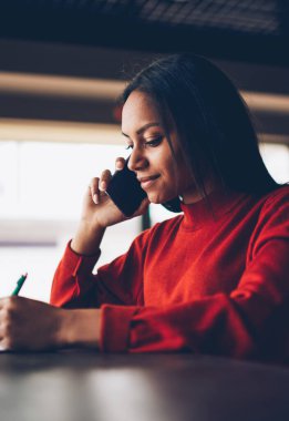 Kafede otururken hizmet bankacılık hakkında bilgi telefon görüşmesi sırasında dikkat çeken genç afroamerican öğrenci konsantre. Rezervasyon istek-e doğru işleç onaylama Yöneticisi koyu derili