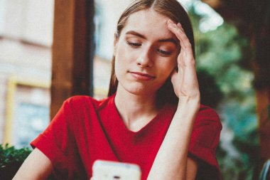 Kafedeki genç kadın blogcu akıllı telefonuyla sosyal ağlar için yeni bir yayın yapıyor, kafası karışmış hippi kız elinde cep telefonuyla internet tarayıcısından son haberleri okuyor.