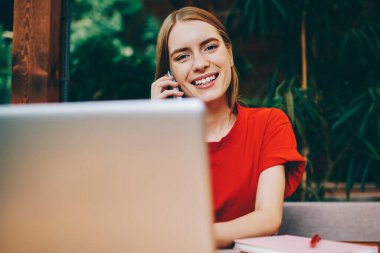 İnternette çalışan gülümseyen kadın yazılım geliştiricisinin portresi Wi-Fi 'ye ve arayan arkadaşına bağlıyken mutlu hippi kız pozitif konuşma sırasında modern netbook' a yeni uygulama yüklüyor.