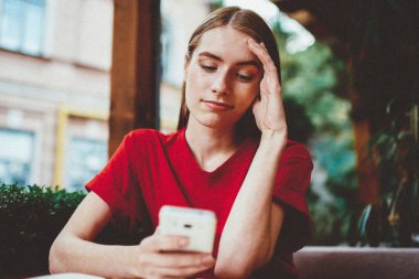 Kafedeki genç kadın blogcu akıllı telefonuyla sosyal ağlar için yeni bir yayın yapıyor, kafası karışmış hippi kız elinde cep telefonuyla internet tarayıcısından son haberleri okuyor.