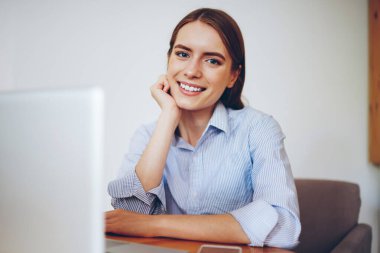 En sevdiği kafeteryada oturan ve yeni modern dizüstü bilgisayarla boş vakit geçiren gülümseyen serbest çalışan kadın portresi. Kapalı alandaki netbook ile uzaktan çalışma sırasında kameraya bakan neşeli hippi kız.