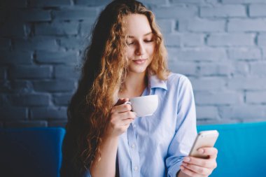 Güzel kadın blogcu kafeteryada çay keyfi yapıyor ve takipçilere akıllı telefon cihazıyla mesajlar gönderiyor. Güzel kadın bir fincan kahve içerken cep telefonundan bildirimi kontrol ediyor.
