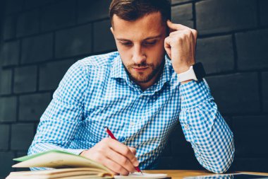 Akıllı erkek öğrenci ders notlar proje ile sorunları çözme accountings yapma kafe iç, dalgın işadamı otururken yazma fikirleri Not Defteri'nde planlama konsantre