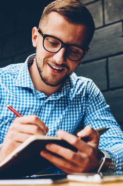 Gözlük yaratıcı erkek Tasarımcısı grafik kafe, pozitif öğrenci kampüs içinde öğrenme Not Defteri'nde fikirler yazma ödev görevleri yerine getirmeye çalışan sketchbook projede planlama yapmaya konsantre