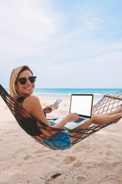 Mutlu başarılı kadın iş serbest laptop süre hamak yalan ve Smartphone'da yaz tatil sırasında tropik adada dolaşım içinde sms mesajı yazarak bir web içeriği için boş ekran alanı ile