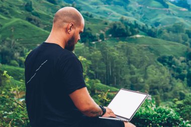 Seyahat ve Uzaktan modern dizüstü bilgisayarda boş bir ekran ve yüksek hızlı 4 g internet bağlantısı güzel yüksek dağlarda yaz gezisi sırasında çalışan erkek sakallı serbest meslek