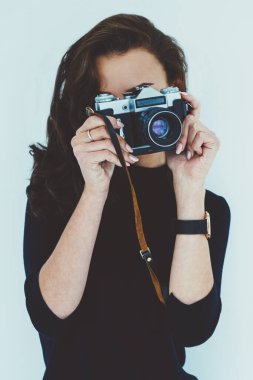 Profesyonel kadın fotoğrafçı fotoğrafları vintage fotoğraf makinesi ayakta reklam metin mesajınız için beyaz promosyon arka plan yapma. Genç kadın boş vaktinizi fotoğraf çekmek