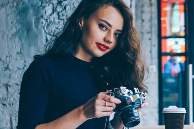 Kablosuz internet'e bağlanan dizüstü bilgisayar oturan vintage fotoğraf makinesi ayarlarını yaparken kameraya bakıyor güzel kadın fotoğrafçı portresi. Kopyalama alanı alanı reklam için