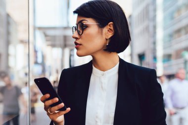 Megalopolis elinde lezzetli kahve ile sokakta yürürken Eyewear ciddi kadın tüccarı. Şık resmi emin işkadını giymek uzakta tutarak cep telefonu ve kahve arıyor