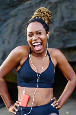 Duygusal olumlu sportif kadın portresi oyuncu smartphone cep telefonu ile komik müzik keyfi etkin elbise giymiş. Neşeli afro Amerikan kadın dinleme şarkıları kulaklık önce spor eğitim