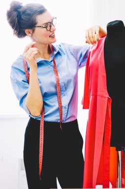 Dikkatli bir şekilde yeni koleksiyonu şık giyim kendi showroom çalışma tasarımını geliştirmek için fikirleri üzerinde düşünürken pembe Tekstil malzeme ile siyah manken seyir yaratıcı kadın modacı