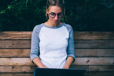 İnternet üzerinden bilgi arayan konsantre bir kız öğrenci kentteki bankta oturmuş, boş zamanlarında internet sitelerine yayın yapan düşünceli genç bir kadın.