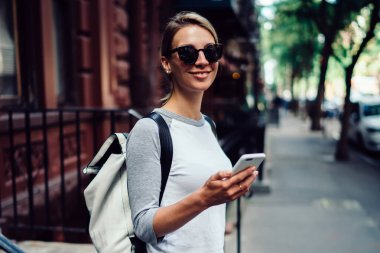 Genç erkek için binayı terk yarım uzunluk portre hippi kız açık havada smartphone online başvuru tarama kamera cep telefonu mesajlaşma şehir merkezinde bir yürüyüş var