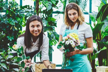 Dizüstü bilgisayarda çiçek kompozisyonu oluşturmaya çalışan profesyonel iş arkadaşlarının portresi, müşteri siparişini tamamlayan çiçek dükkanı sahibi kadın çalışan asistanı