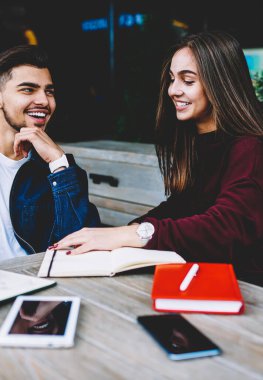 Neşeyle dostça konuşma yaparken gülümseyen mutlu kadın ve erkek öğrenciler, Teras kafe üzerinde oturan ortak projeler üzerinde çalışma neşeli arkadaşlarım şaka ve tartışma sırasında gülüyor
