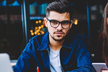 Onun iş arkadaşı onu arkadaş proje üzerinde çalışmak için mobil kullanmayı durdurmak için bekleyen hipster adam görmezden telefonu üzerinden sosyal ağlar sohbet ederken kamera arayan genç ciddi erkek öğrenci