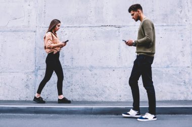 Tanıtım alanı yakınında sokakta yürürken gençlerin teknoloji online, vakit erkek ve dişi hipsters sosyal ağlar ve dijital cihazlar için bağımlısı akıllı gezinme yoğunlaşmıştır.