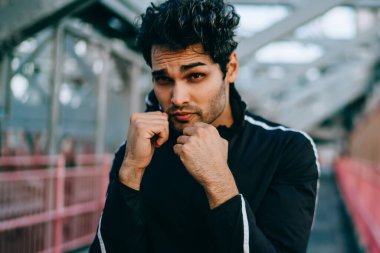 Sakallı uygun adam portresi boks kentsel ortamda açık havada daha iyi fiziksel form için çalışmaktadır. Gençlik sporcu adam elleriyle yüzünü daha önce egzersiz sırasında sıcak spor egzersizleri yapıyor yakınındaki