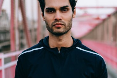 Kamera ayakta Köprüsü'nde kentsel ortamda bakarak motive sakallı jogger kırpılmış görüntü sahte alanı için sportif etiket ile siyah eşofman giymiş