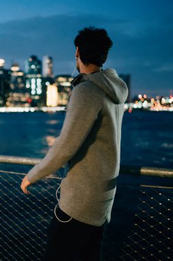 Sporcu arkadan görünüm akşam şehir sahne ayakta açık havada Nehri yakınında zevk gri eşofman giymiş. Etkin aşınmaya kentsel bir ortamda yürüyüş kasaba durig gecesi arıyorum erkek koşucu