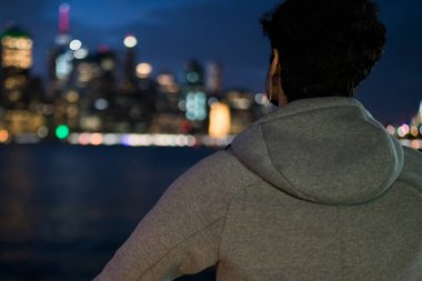 Genç adam Arkadan Görünüm alanı markası ayakta akşam şehir arka plan üzerinde kentsel ortamda için sahte gri spor ceket giymiş. Active giysi sporcu spor giyim etiketli, twilight