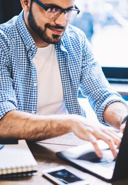 Bilgi ağları üzerinden arama netbook klavye olumlu hipster adam kafede otururken online para kazanmak uzak iş dizüstü bilgisayarda yazarak yetenekli erkek serbest meslek