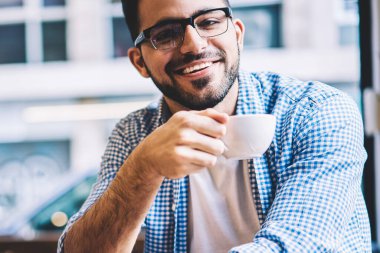 Zengin erkek portresi bu netbook, başarılı freelancer Kupası ve bloglama ağlarda tutan kamera bakarak web sayfasında dosya indirmeyi kafede kahve aroması tadını geliştirici