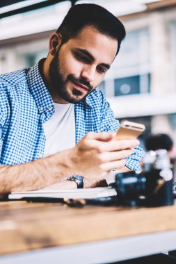 Genç adam akıllı telefon donanımları, bildirim uzak iş yaparken hücresel güncelleştirme yazılımı üzerinde kontrol hipster adam ile yer coworking yılında serbest çalışan ağlarda gelir mesaj okuma