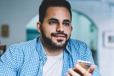 Kafe iç, düşünceli erkek Blogger uzak iş arama için bekleyen smartphone tutan düşünceli sakallı adam telefonu kafede ağlarında dosya yükleme yaratıcı bir fikir konsantre