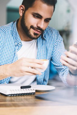 Haber ağları üzerinden smartphone telefon uygulaması ve 4 g bağlantı kullanarak multimedya İndiriyor kafede çalışan erkek serbest meslek kafede oturan okuma genç hipster adam sakallı