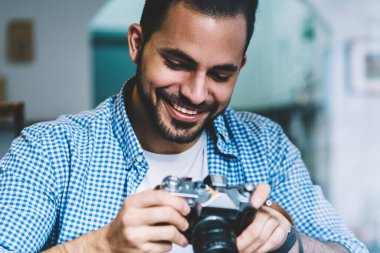 Yaratıcı işgal Café, mutlu hipster adam hobi ekipman resimleri görüntüleme çekim zevk oturan vintage fotoğraf makinesinde ayarları kontrol başarılı erkek fotoğrafçı memnun