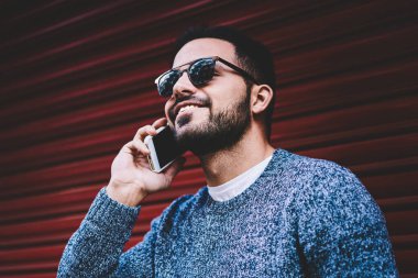 Cep telefonu ucuz tarifs gezici ayakta trendy kıyafeti telefon görüşmesi ile bağlantı memnun olan erkek kişi kentsel ayarları kullanarak üzerinde konuşurken gülümseyen genç hipster adam