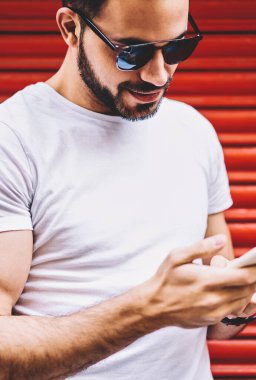 Yakışıklı genç marka adını posta smartphone, hipster adam ağ ve bloglama modern hücresel harcama zaman açık havada üzerinden kontrol gelir mesaj okuyor kopya alan ile Beyaz gömlekli