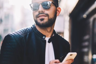 Hücresel paylaşımı Multimedya uzağa istimal kullanma smartphone üzerinde açık havada sohbet için online sokak, yakışıklı erkek irsal metin haber seyir ağlarda sakallı adam Resim kırpılmış