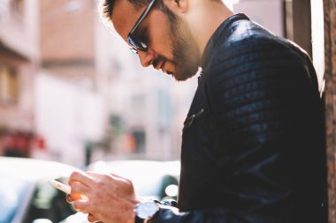 Hipster adam açık havada, yakışıklı erkek multimedya mesajları modern telefon ve 4 g bağlantısı üzerinden internet'e gönderme ayakta uygulamada kafeler arama için smartphone kullanarak görüntü kırpılmış