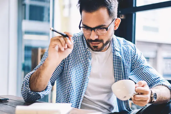 De kahve iç oluşturma projesi, genç erkek gazeteci Kupası kafeteryada oturan içecek ile tutarak defter yazıda üzerinde durulması için profesyonel grafik tasarımcı çalışma