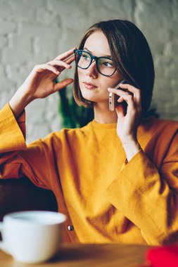 Kendine güvenen kadın girişimci Smartphone'da dolaşım çağrı telefon görüşme sırasında iş sorunu çözme. Hücresel kapalı kafeteryada oturan arkadaşı ile konuşurken kafe dalgın sahibi