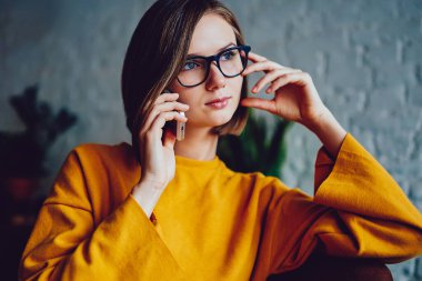 Kısa saç tıraşlı, düşünceli, akıllı telefon konuşmalarında, kahve dükkanında oturan düşünceli bir kadın sahibi. Kafede cep telefonuyla konuşan bir iş kadını.