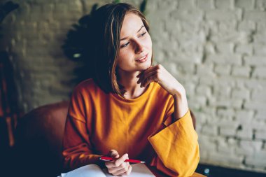 Kafede lezzetli kahve ile oturan gelecekteki proje planlarını yazmaya kısa saç kesimi rüya ile düşünceli öğrenci. Pencereden dışarı bakıyor ve hedefleri üzerinde düşünme düşünce gülümseyen öğrenci
