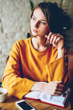Yaratıcı fikirler ile defter ile kahve masada oturan hakkında düşünceli akıllı kadın düşünme. Rüya gibi işkadını pencere gün kafeteryada oturan planları üzerinde durulması dışında arıyorsunuz