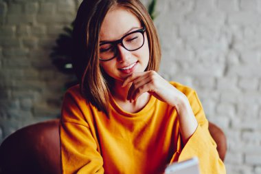 Görme düzeltmesi için gözlüklü genç kadın 4G interneti kullanarak akıllı telefondan uyarı alırken gülüyor. Neşeli kadın blogcu telefon uygulaması yüklüyor.