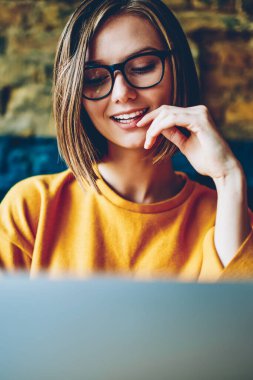 Gözlük ve sosyal ağlarda modern bilgisayarda kafede oturan ücretsiz yüksek hızlı internet bağlantısı kullanarak arkadaşıyla Sohbet online kısa saç kesimi ile neşeli çekici kız öğrenci